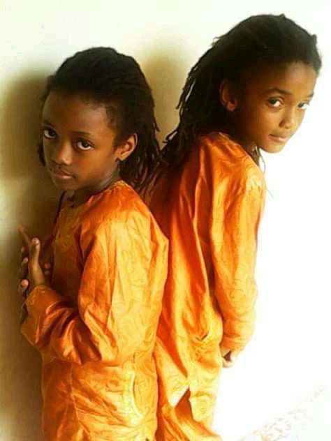 Young Jacob and Joseph Sesay back-to-back in orange traditional dress